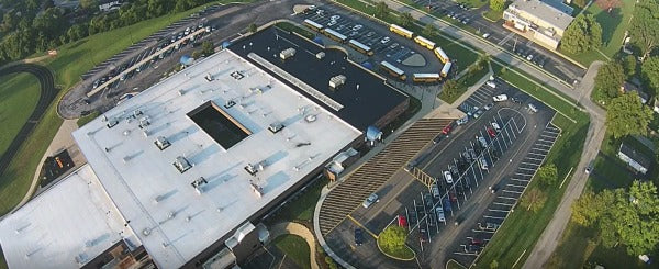 Aerial view of a school and parking lots with buses queued up for student pickup