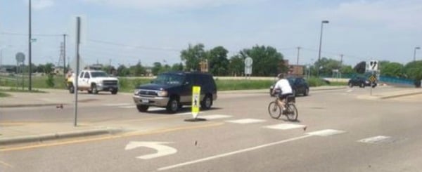 Cars and bicyclist maneuvering through an intersection in close proximity