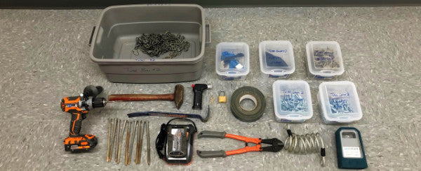 Field work bin with all of the hardware used for data collection laid on the floor. hardware includes nails, hammers, drill, tape, padlocks, cable locks, and tube counters