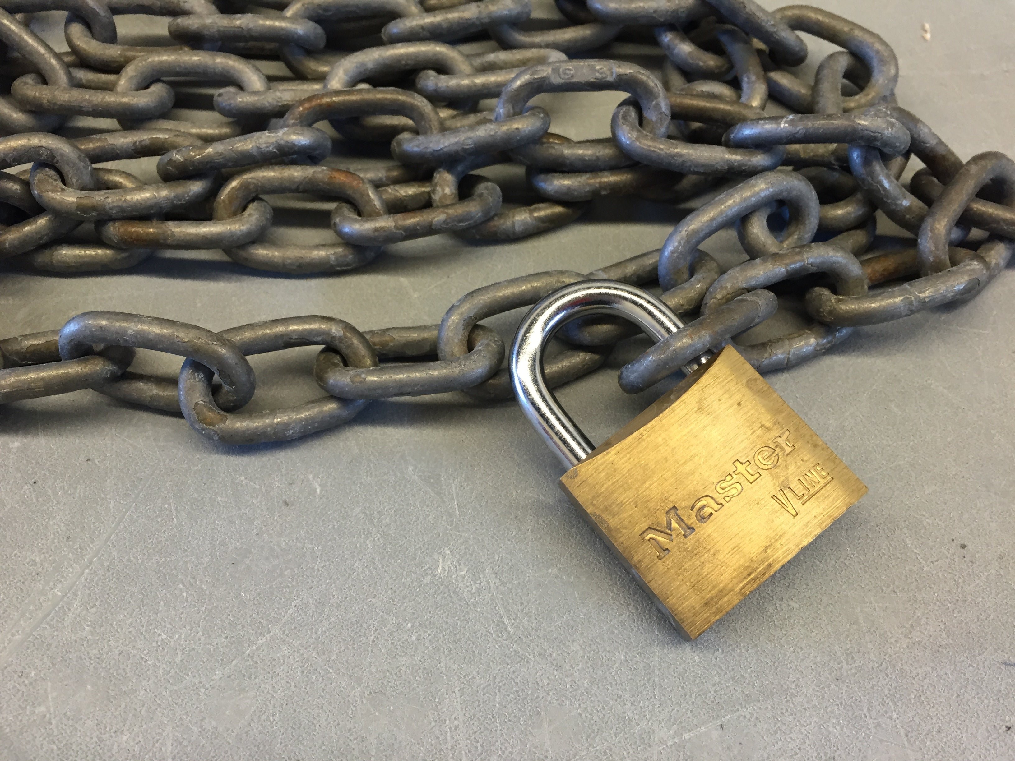a gold Master Lock padlock attached to a coiled steel chain