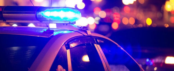 a close up of a police car, at night, with blue flashing lights turned on