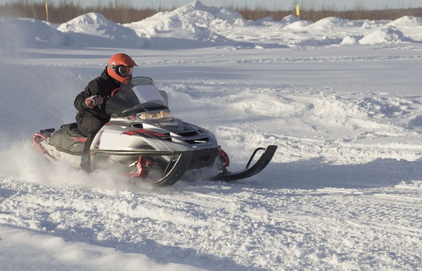 A snowmobile and rider on flat groomed snow.