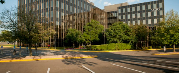 office building surrounded by trees and empty parking lot