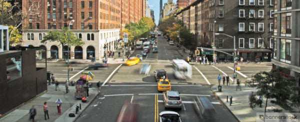 Aerial view of an intersection with a blur of cars, taxis, buses, and pedestrians moving along and through it.