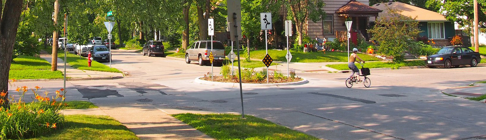 Mini roundabout in a residential neighborhood with a bicyclist travelling through the intersection