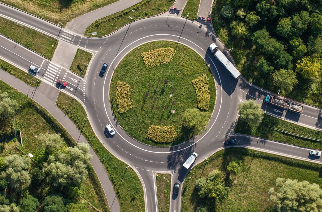 Aerial view of a two lane roundabout with trucks and cars entering and exiting the legs